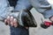 Man farrier using pick knife tool to clean horse hoof, before applying new horseshoe. Closeup up detail to hands holding wet