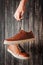 Man fashion concept. Hand holds for laces brown leather male shoes on a dark background