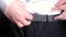 Man fastens gray belt tightly. Slow motion close-up of costume dressing process.