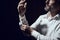 A man fastens his sleeves and cufflinks on white shirt in dark studio room