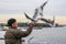 A man feeding a flock of seagulls in the Yokohama port. Birds in the city.