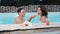 Man feeding his woman with sushi into a swimming pool. Happy couple eating sushi in pool.