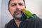 Man feeds green parrot with mouth, parrot agapornis roseicollis