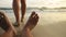 The man feet relaxed are lying on the sandy beach and washed by the water and foam of the ocean. Women& x27;s feet are