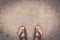 Man feet wearing some brown flip flops standing on the asphalt concrete floor