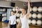 Man With Female Friend Lifting Kettlebell In Gymnasium