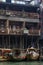 A man in Fenghuang Ancient City peers over a balcony at a row of tour boats in the Tuo Jiang River below