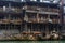 A man in Fenghuang Ancient City peers over a balcony at a row of tour boats in the Tuo Jiang River below