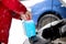 Man filling antifreeze coolant for cleaning front window with snow in background.