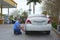 Man filling car tire with air at a gas station with a coin operated compressor pump