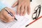 Man filling OMR sheet heading with pen. Picture of glasses and pencil on the table.