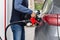 Man fills his black car with fuel at gas station, pumps up gasoline fuel injector for refueling