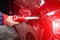 A man fills up a car's tank with gasoline at an equipped gas station. A hand holds a refueling gun in the tank of the