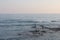 A man is fishing with a fishing rod near a rocky shore. Fisherman on the beach in Alanya. Fishman stands on the rocks in