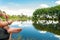 Man fishing, holding a rod on a lake with a beautiful nature around.