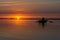 Man Fishing On A River From The Wooden Boat At Sunset . Fisherman Boat Rowing