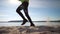 Man in fitness clothing running along sandy beach. Runner athlete feet running on sand. Fitness silhouette sunrise jog, workout