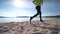 Man in fitness clothing running along sandy beach. Slim middle age man running along the seashore at sunset