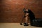 Man after fitness session, talking on the phone while sitting on a rubber wheel against a brick wall background