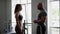 A man fitness trainer and a girl client in the gym have contented conversation after finishing a workout. A girl athlete