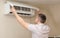 A man fixes the air conditioner, cleans the filters from dust, checks the performance