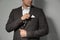 Man fixing handkerchief in breast pocket of his suit on light grey background, closeup