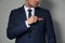 Man fixing handkerchief in breast pocket of his suit on light grey background, closeup