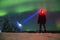 Man with flashlight Colorful Northern lights & x28;Aurora Borealis& x29; with red oxygen glow above a forest. Russia, Arkhangelsk