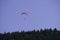 A man flies a paraglider from the mountain, surrounded by forests. flying under wing. outdoor activity