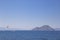 A man flies on a paraglider over the sea, following a boat that