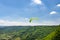 Man flying a green paraglider over beautiful wineries in Germany, visible river and forest.