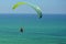 Man is flying on green paraglider in the sky above the azure sea. Balance, extreme sports, lifestyle. Mediterranean Sea Israel