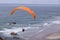 A man flying a paraglider over beach of Cape Kiwanda State Natural area
