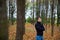 A man with folded arms looks at the sky and stands in an autumn forest,the leaves are yellow and have fallen from the trees,