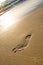 Man foot print on a white sand beach