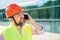 A man foreman in a construction helmet answers phone call