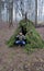 Man in the forest autumn, spring, winter season. Primitive survival debris hut. Blanket, shelter in the forest.