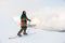 Man freerider in colorful suit with skis near snow-covered mountain slope