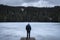 Man on frozen lakeshore on cold winter day