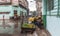 Man with fruit cart sits sheltering from heavy rain hoping to sell while others walk on street