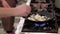 Man frying champignons standing at stove in kitchen.