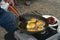 Man frying eggs on outdoor propane camp stove