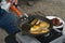 Man frying eggs on outdoor propane camp stove