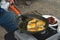 Man frying eggs on outdoor propane camp stove