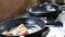 Man frying slices of fish on hot pan.