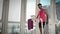 Man in funny pink outfit starts to exercise on home smart running trainer. Young male athlete is walking on treadmill in the morni