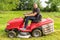 Man gardener driving a riding lawn mower in garden