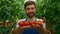 Man gardener holding tomatoes harvest in green countryside garden smiling