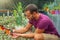 Man gardener holds a pot in his hand and examines the seedlings of mammillaria cacti. Growing and caring for plants and flowers in