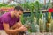 Man gardener holds a pot in his hand and examines the seedlings of mammillaria cacti. Growing and caring for plants and flowers in